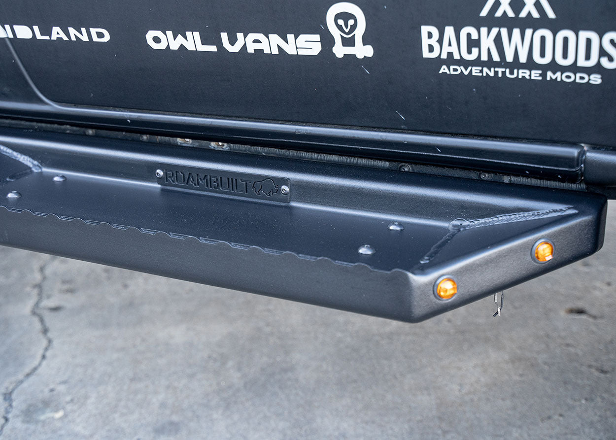 Close-up of ROAMBUILT Flat Side Step on Mercedes Sprinter showing small integrated lights, raised grip edge, and textured black aluminum surface.