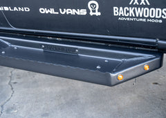 Close-up of ROAMBUILT Flat Side Step on Mercedes Sprinter showing small integrated lights, raised grip edge, and textured black aluminum surface.