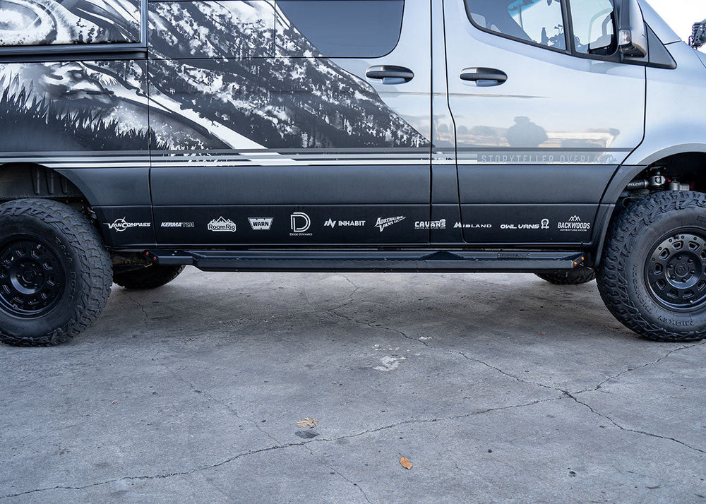 Direct side profile of ROAMBUILT Flat Side Step in black textured aluminum, mounted on a Mercedes Sprinter, showing full length and clearance.