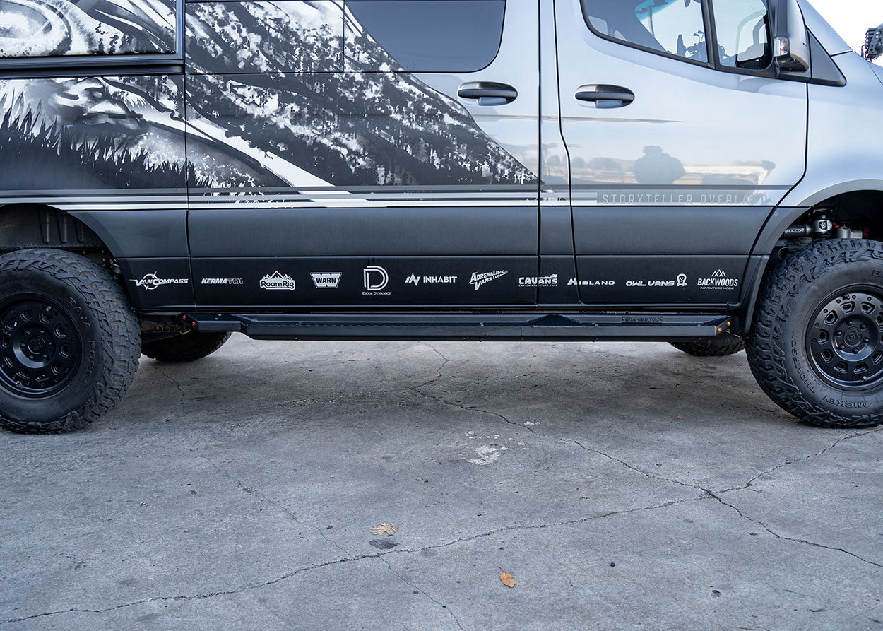 Direct side profile of ROAMBUILT Flat Side Step in black textured aluminum, mounted on a Mercedes Sprinter, showing full length and clearance.