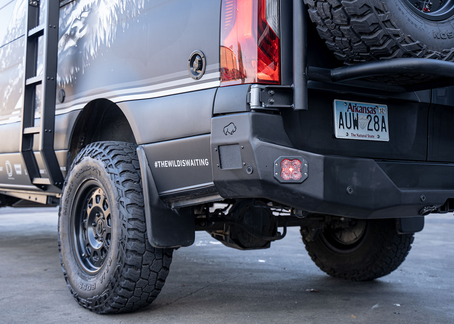Driver-side view showing the left half of the ROAMBUILT Rear Bumper on a Mercedes Sprinter van, highlighting the contoured aluminum design, integrated step, clean welds, and built-in sensor housing for a functional and rugged upgrade.