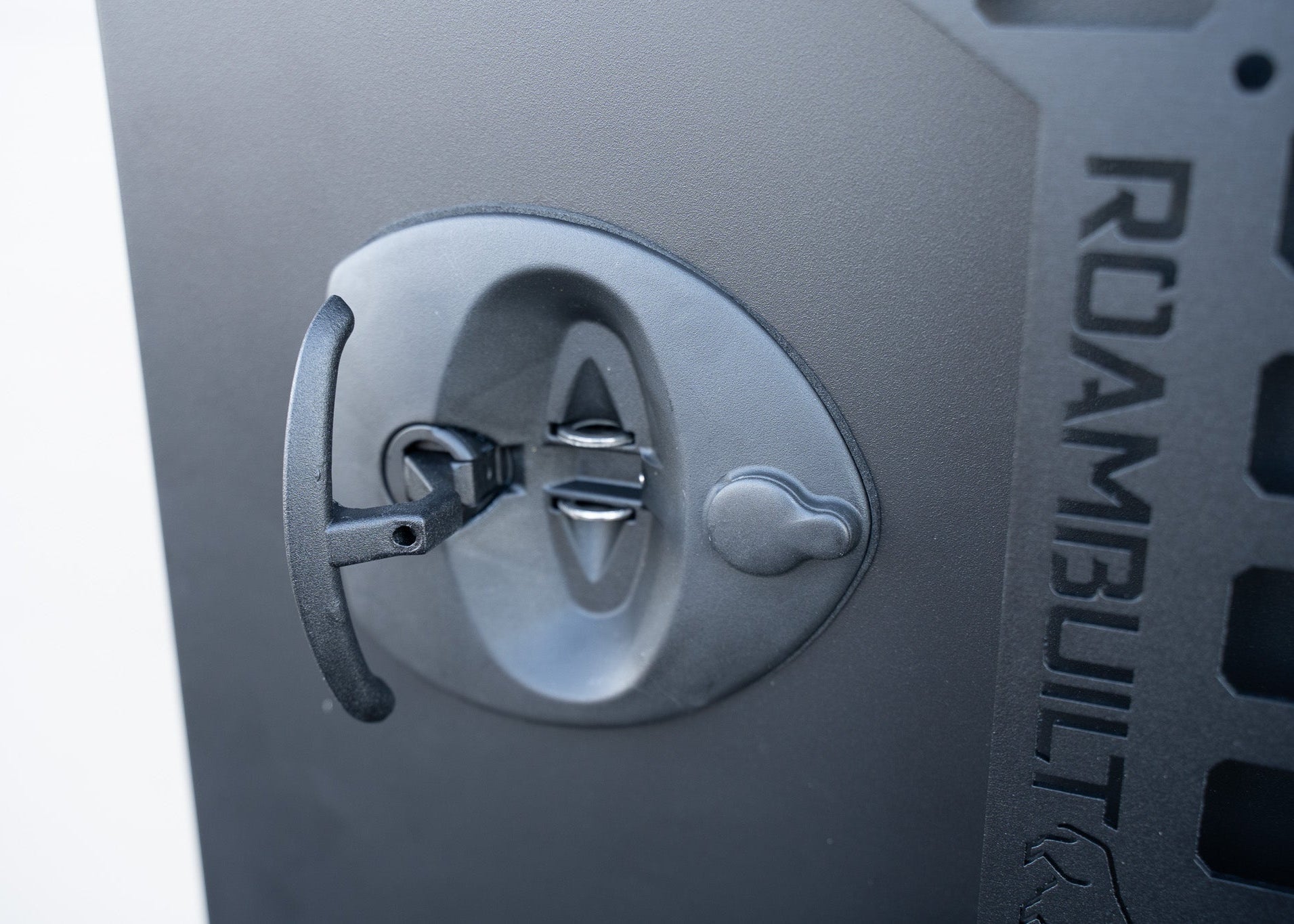 Close-up of the black lockable compression latch on the ROAMBUILT Universal Aluminum Storage Box, highlighting the durable hardware and textured powder coat finish.