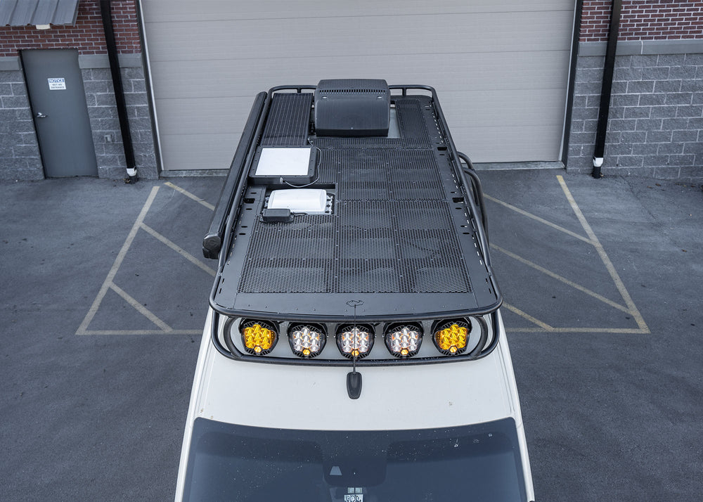 Overhead view from the front showing the entire ROAMBUILT Safari 2.0 roof rack with curved front and up to five mounted Baja Designs LP9 lights on a Mercedes Sprinter chassis built by Storyteller Overland