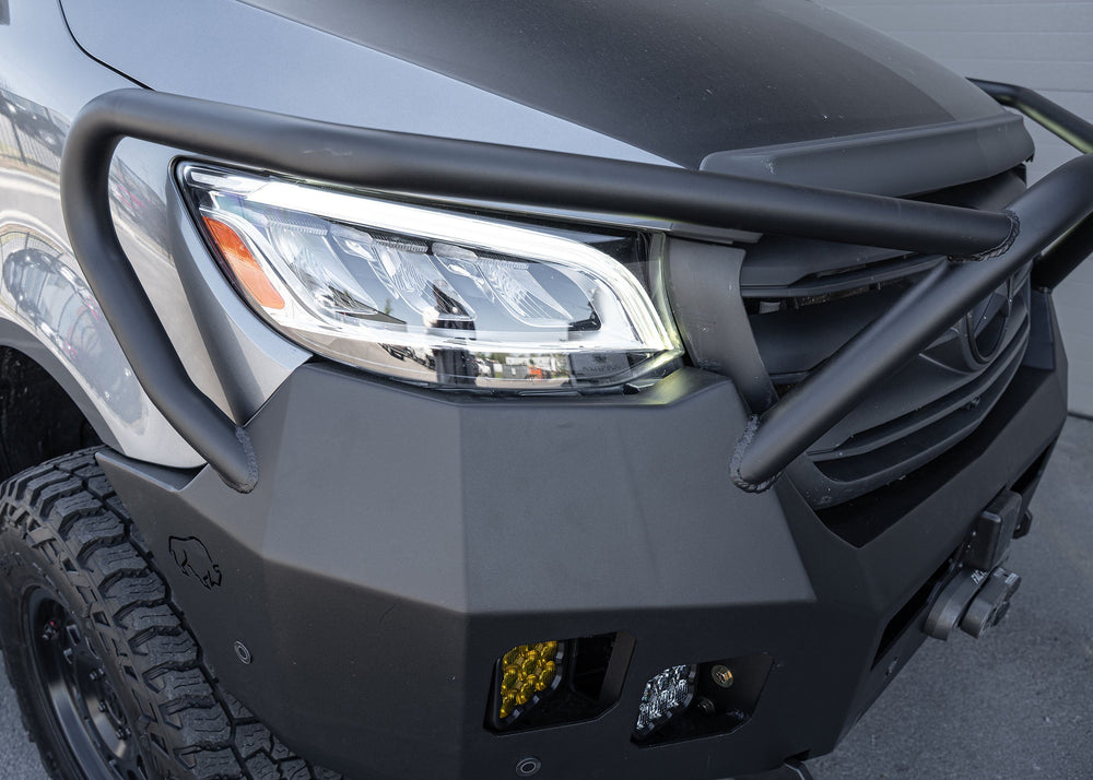 Top-side passenger view of a Mercedes Sprinter van featuring the Full Guard Front Bumper, showcasing its contoured fit, hybrid steel and aluminum build, and detailed design elements like light pockets and winch mount for robust, lightweight front-end protection