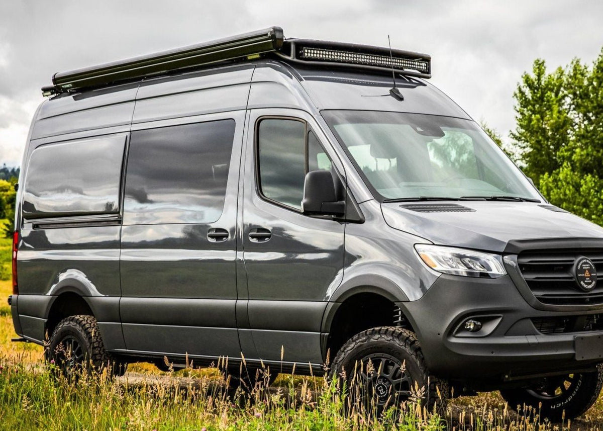 Passenger side view of SafariRack 2.0 SLB mounted on a 2007+ Mercedes Sprinter van, showing curved front profile, perforated decking, and rugged aluminum design.