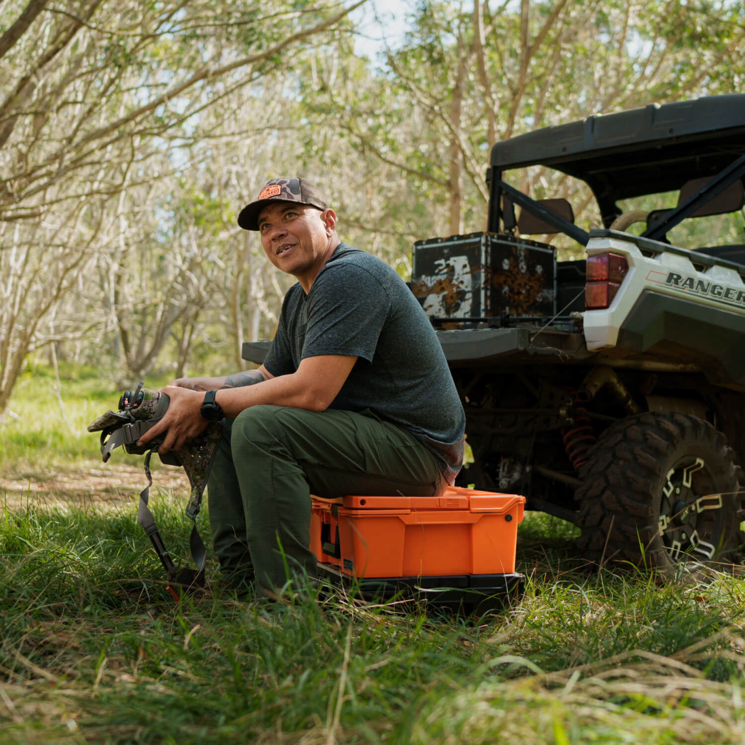 [A0020-HRAK-ORG] DECKED ambassador, Justin Lee, sitting on his Blaze Orange Halfrack. His side-by-side is in the background.