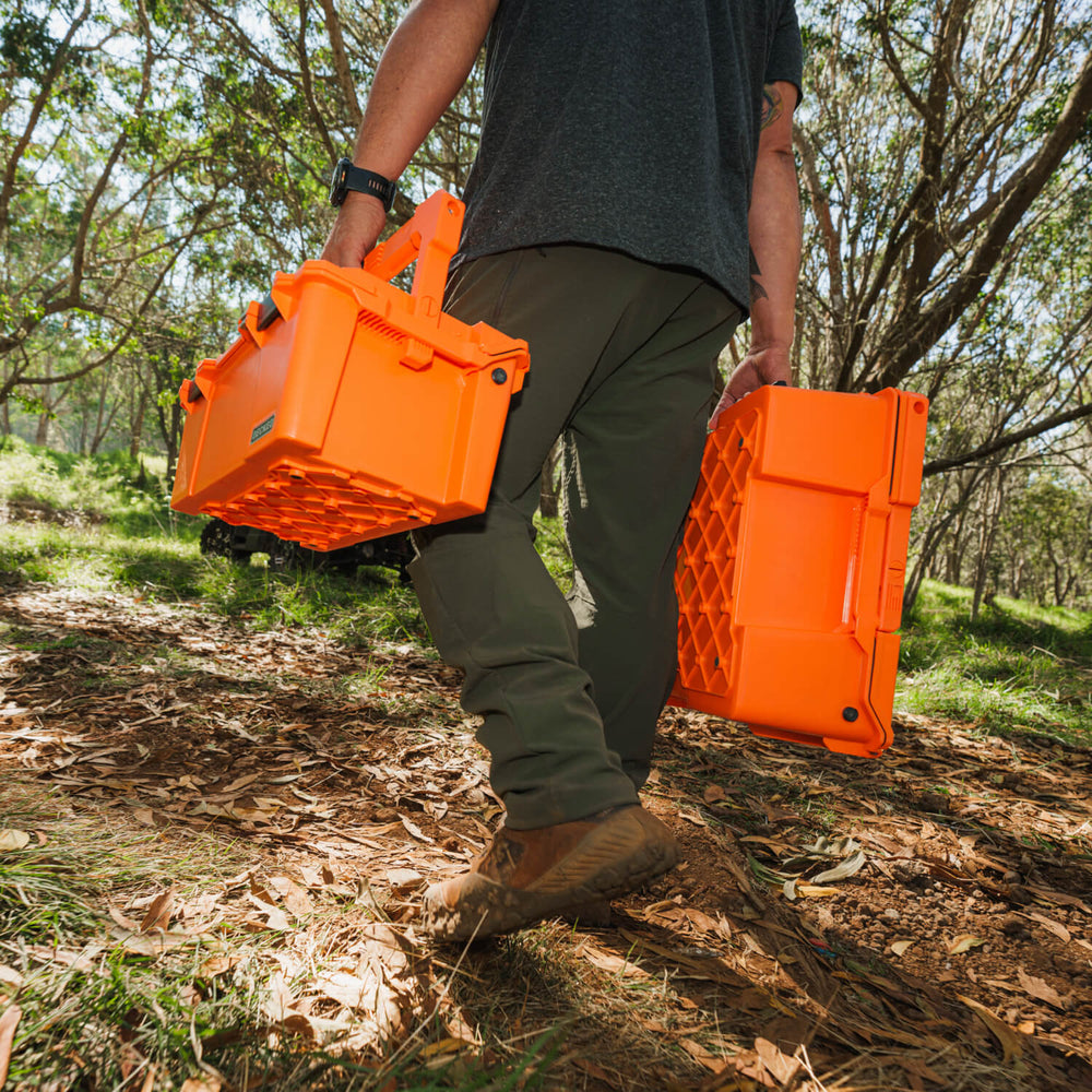 [A0010-SIXR-ORG] A man carrying the Blaze Orange Sixer and Halfrack D-co cases. The orange of the cases pops in the woods, making them easy to spot.