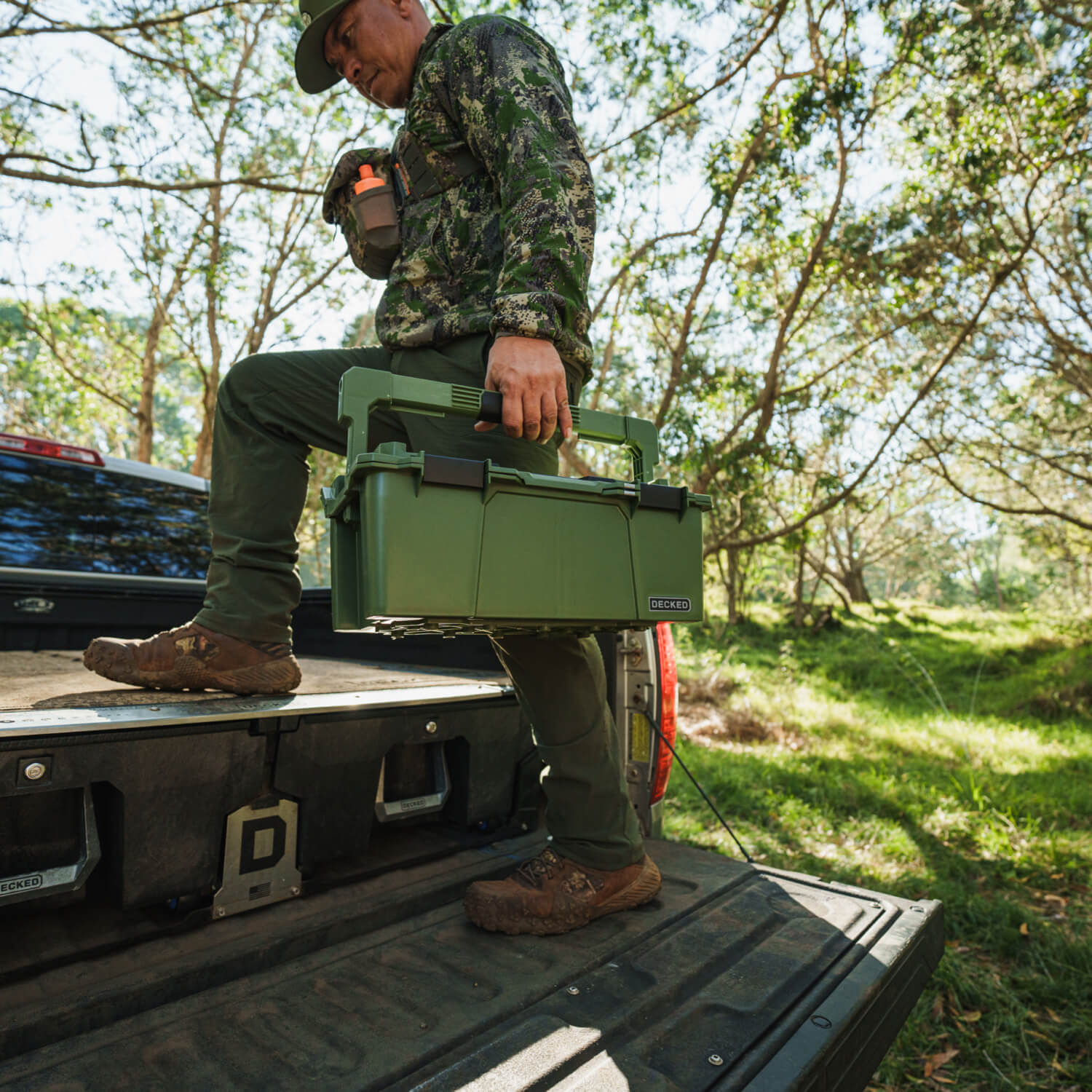 [A0010-SIXR-GRN] A hunter stepping up onto his DECKED Drawer System with his Ranger Green Sixer D-co Case in hand.