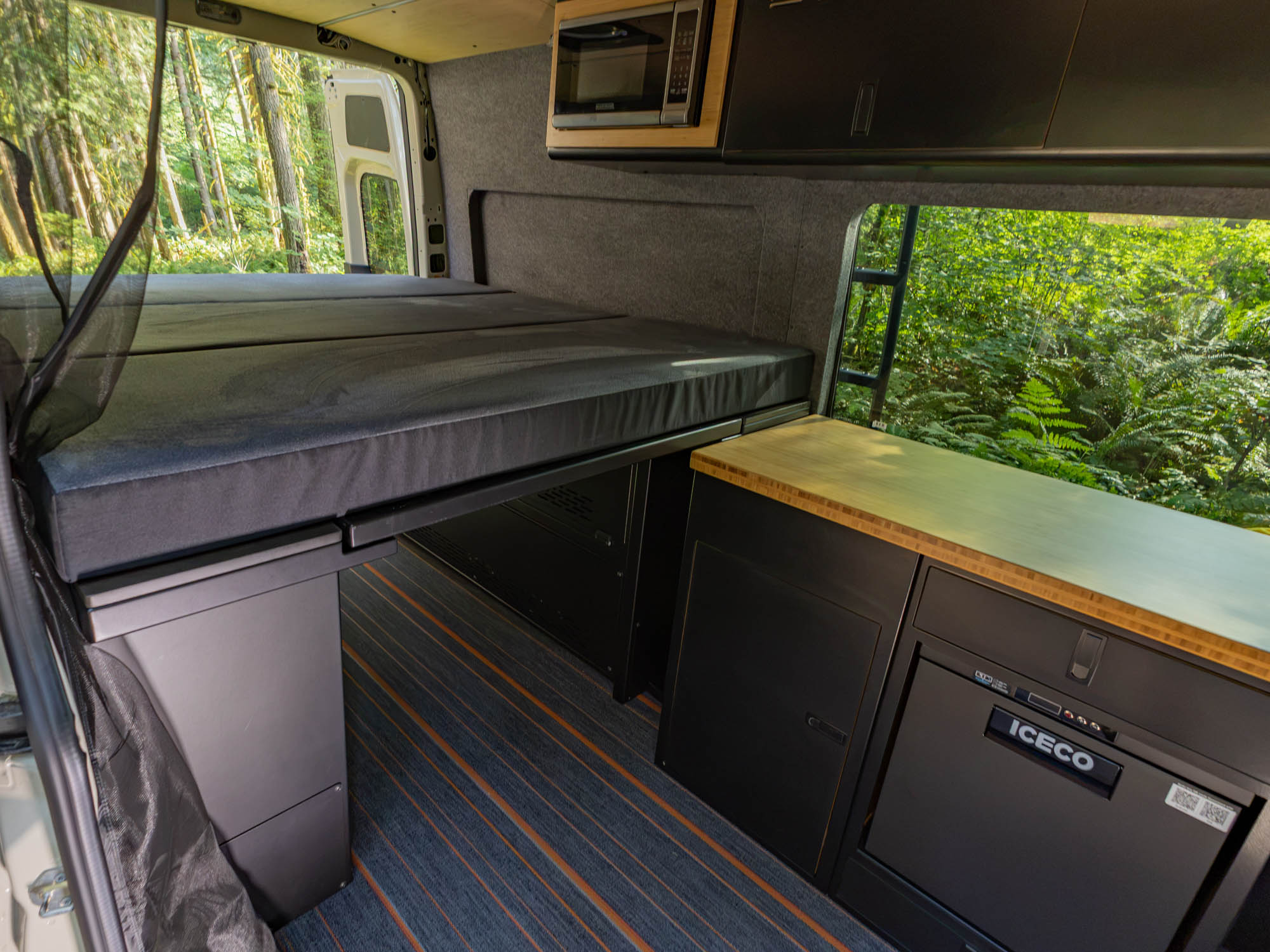 Angled view of Modular Cabinet Bed System for Sprinter & Transit in North-South orientation installed in finished camper van 