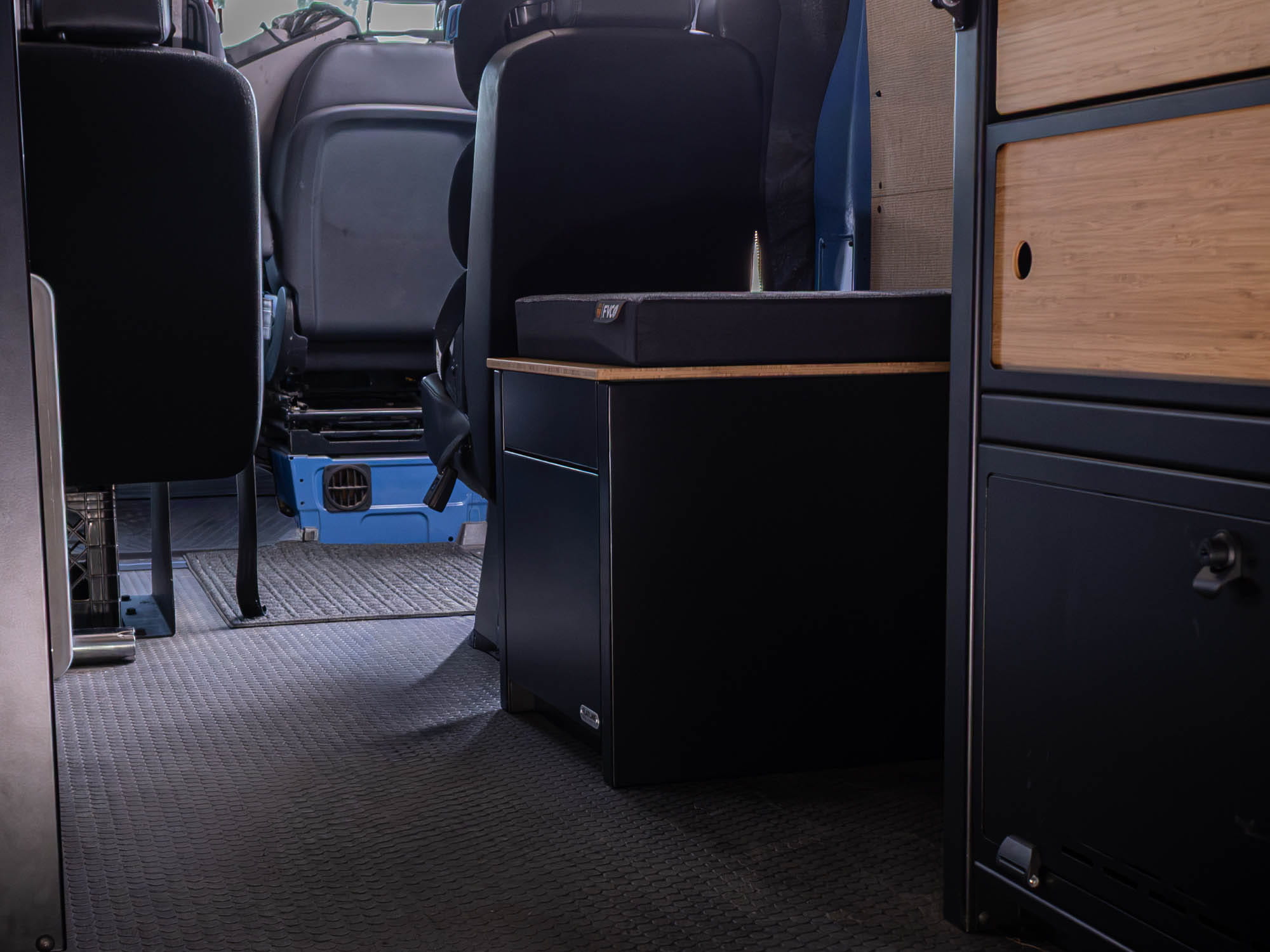 View of Portable Toilet Storage Cubby with bench seat pad on top from rear of van