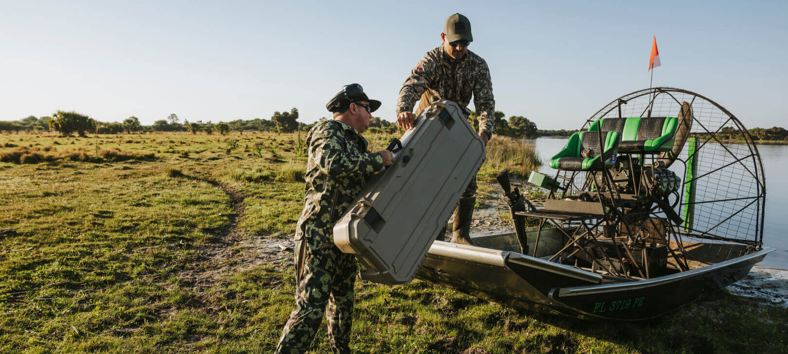 [A0030-MMAN-TAN] @expanded Two men loading a Desert Tan Honcho into their airboat