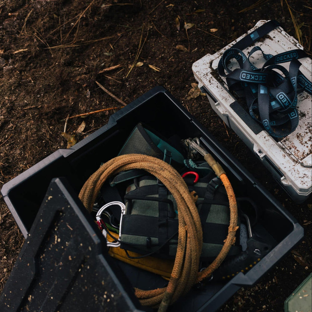[A0041-DBIN-BLK, A0040-DBIN-BLK] Saddle hunting gear inside of a black Payloader Bin on a forest floor.