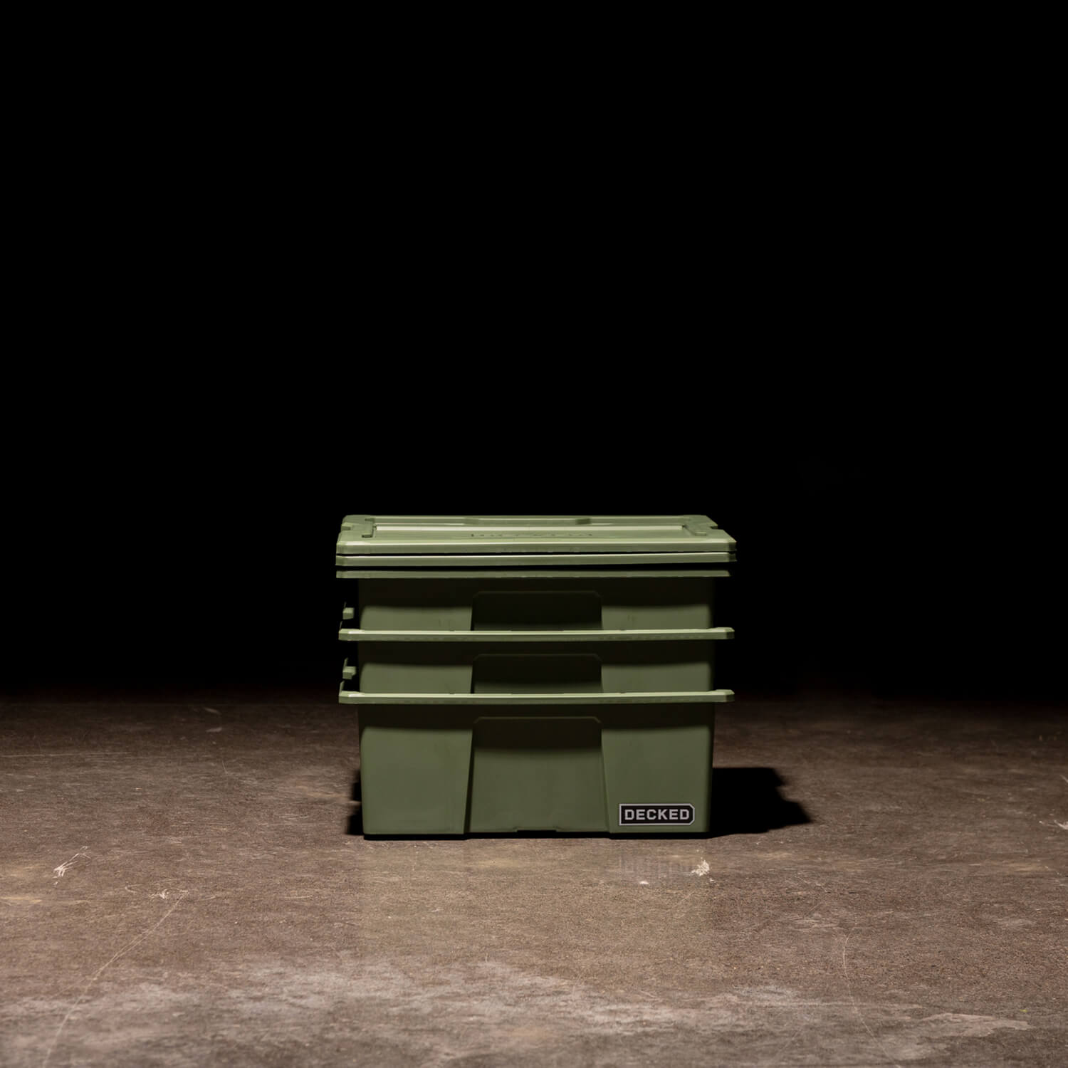 [A0041-DBIN-GRN, A0040-DBIN-GRN] Three ranger green Payloader Bins nested together with the lids sitting on top in a garage with a dark, shadowy background.