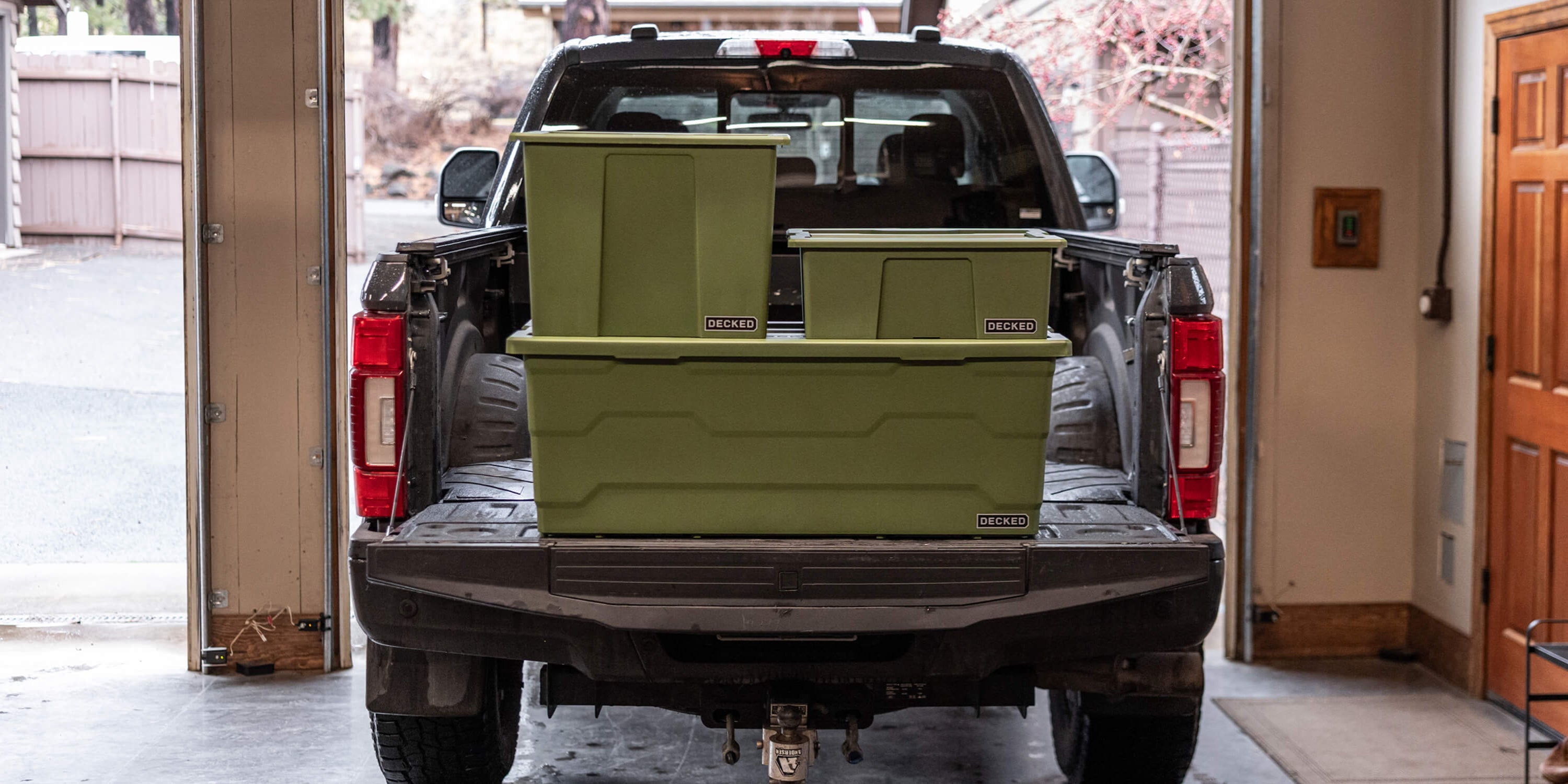 [A0041-DBIN-GRN] @expanded The three ranger green Payloader sizes stacked on the tailgate of a truck in a garage.