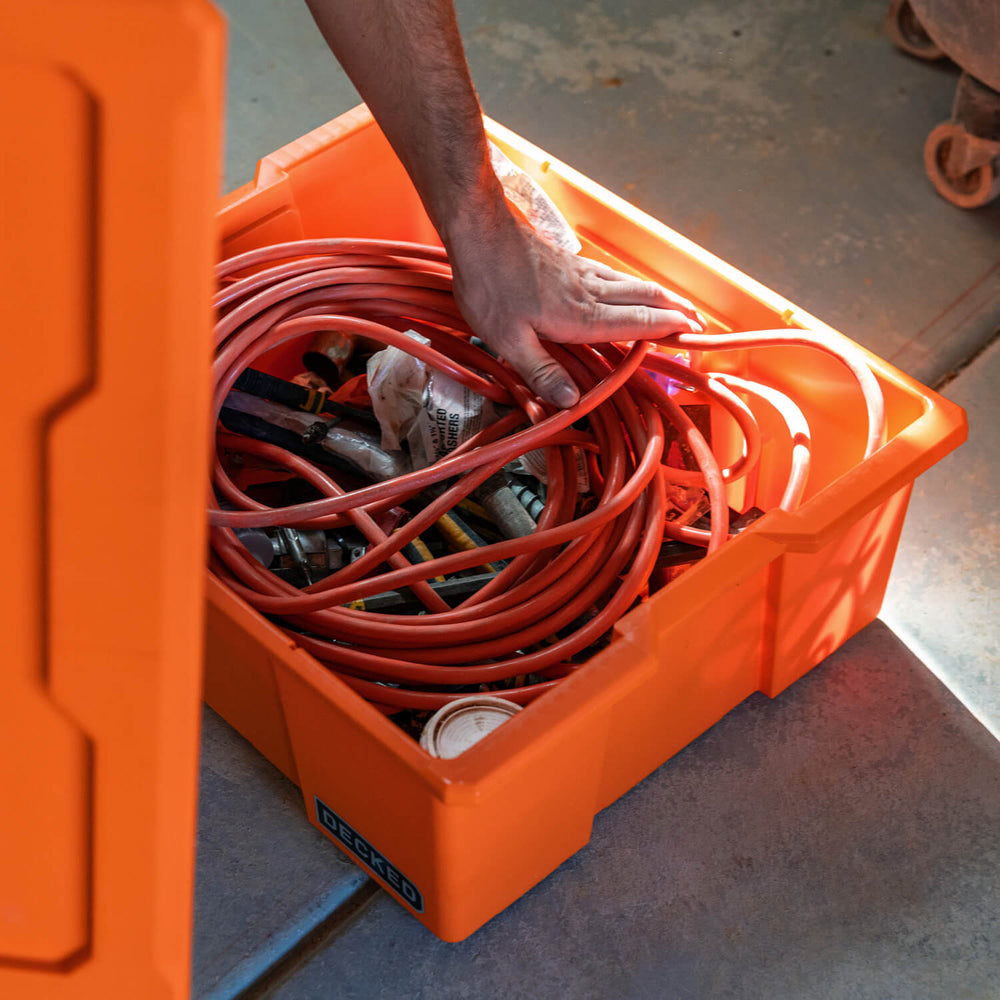 [A0041-DBIN-ORG, A0040-DBIN-ORG] A man placing an extension cord and other small tools in his blaze orange Payloader Bin.