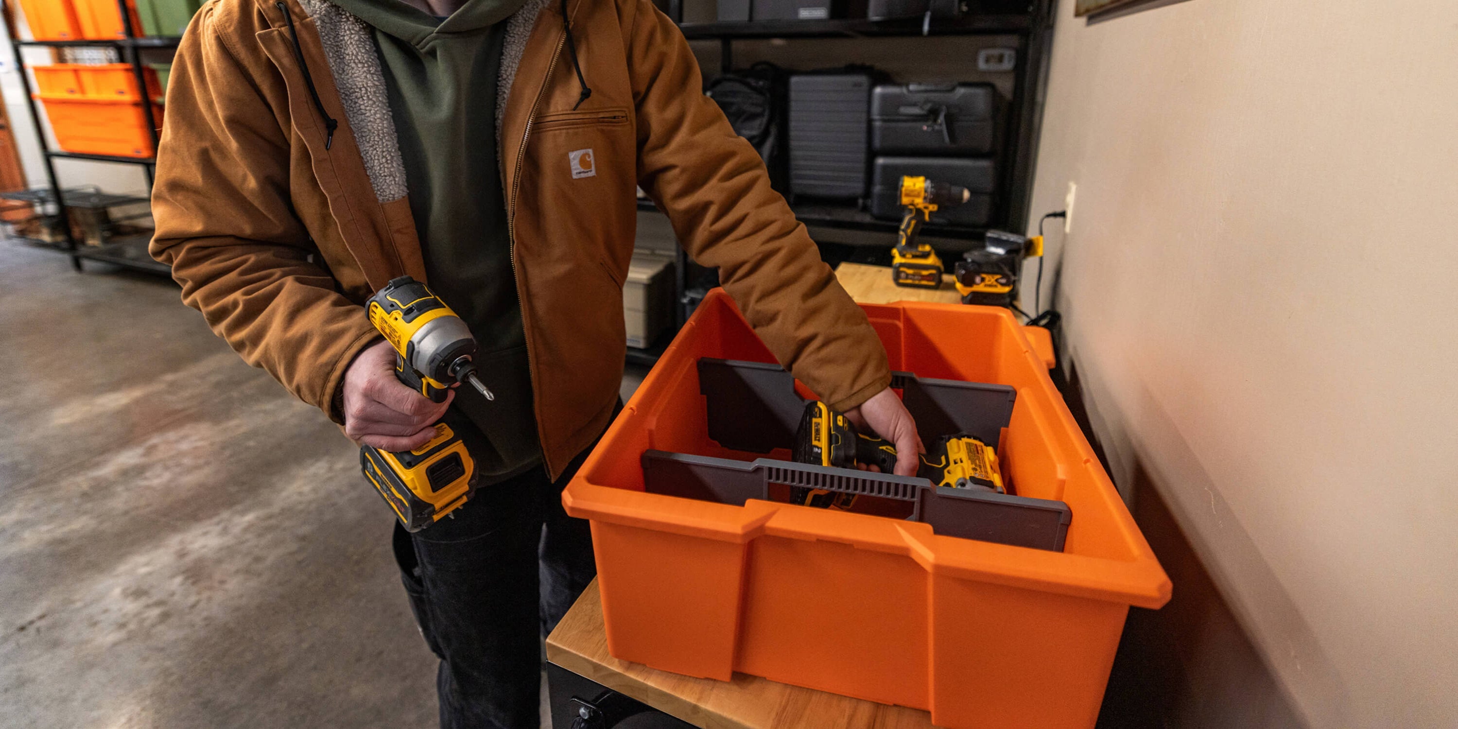[A0041-DBIN-ORG, A0040-DBIN-ORG] @expanded A man organizing power tools in his weatherproof and rugged blaze orange DECKED Payloader Bin.