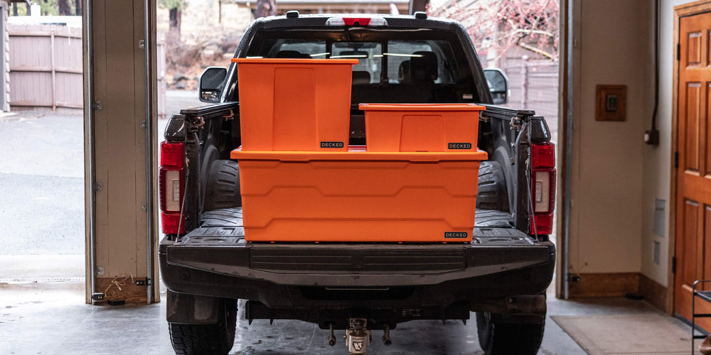 [A0041-DBIN-ORG] @expanded The three blaze orange Payloader sizes stacked on the tailgate of a truck in a garage.