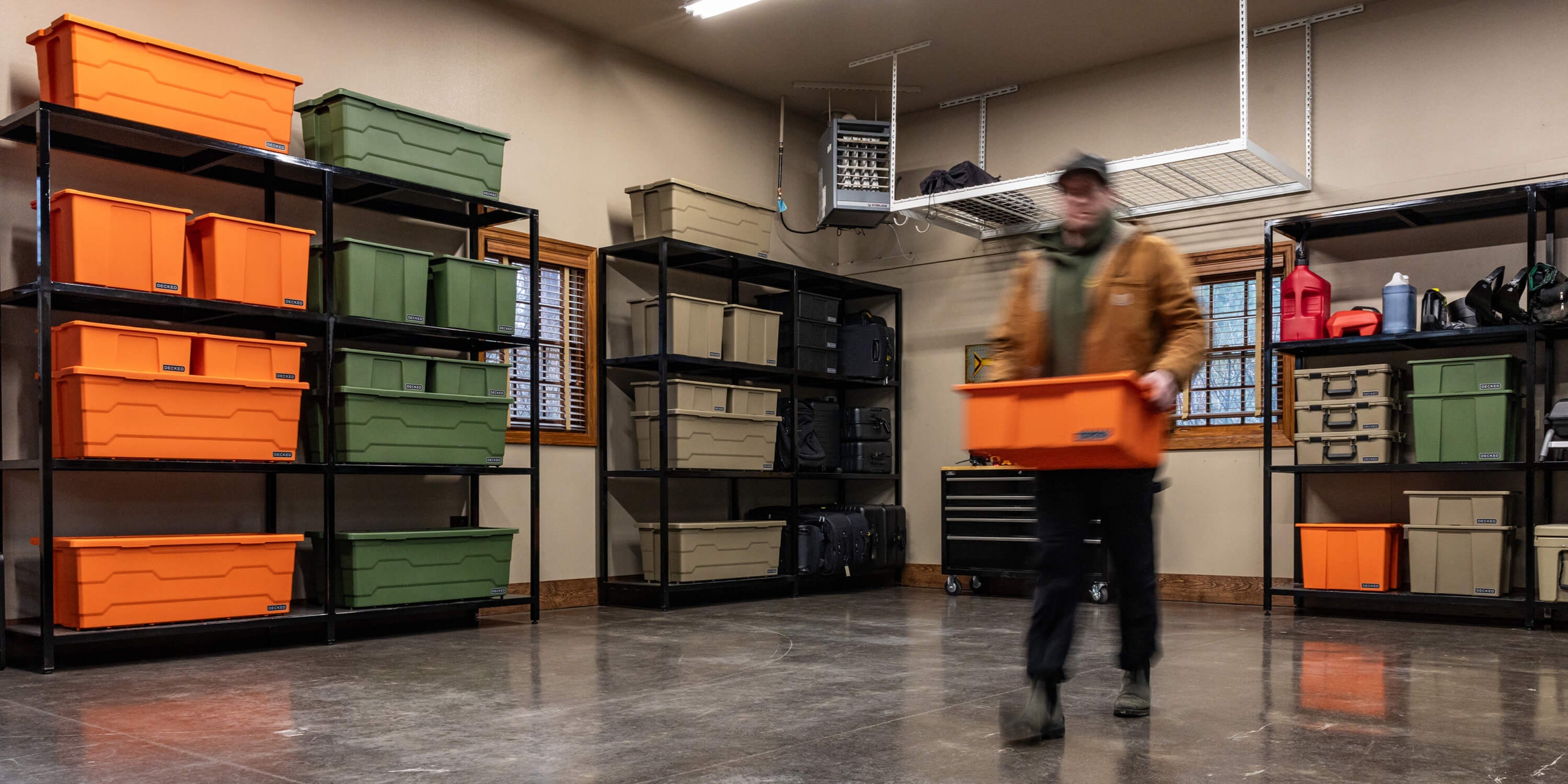 [A0040-DBIN-ORG] @expanded A man carrying a blaze orange Payloader Bin from a storage bin in his garage to his vehicle.