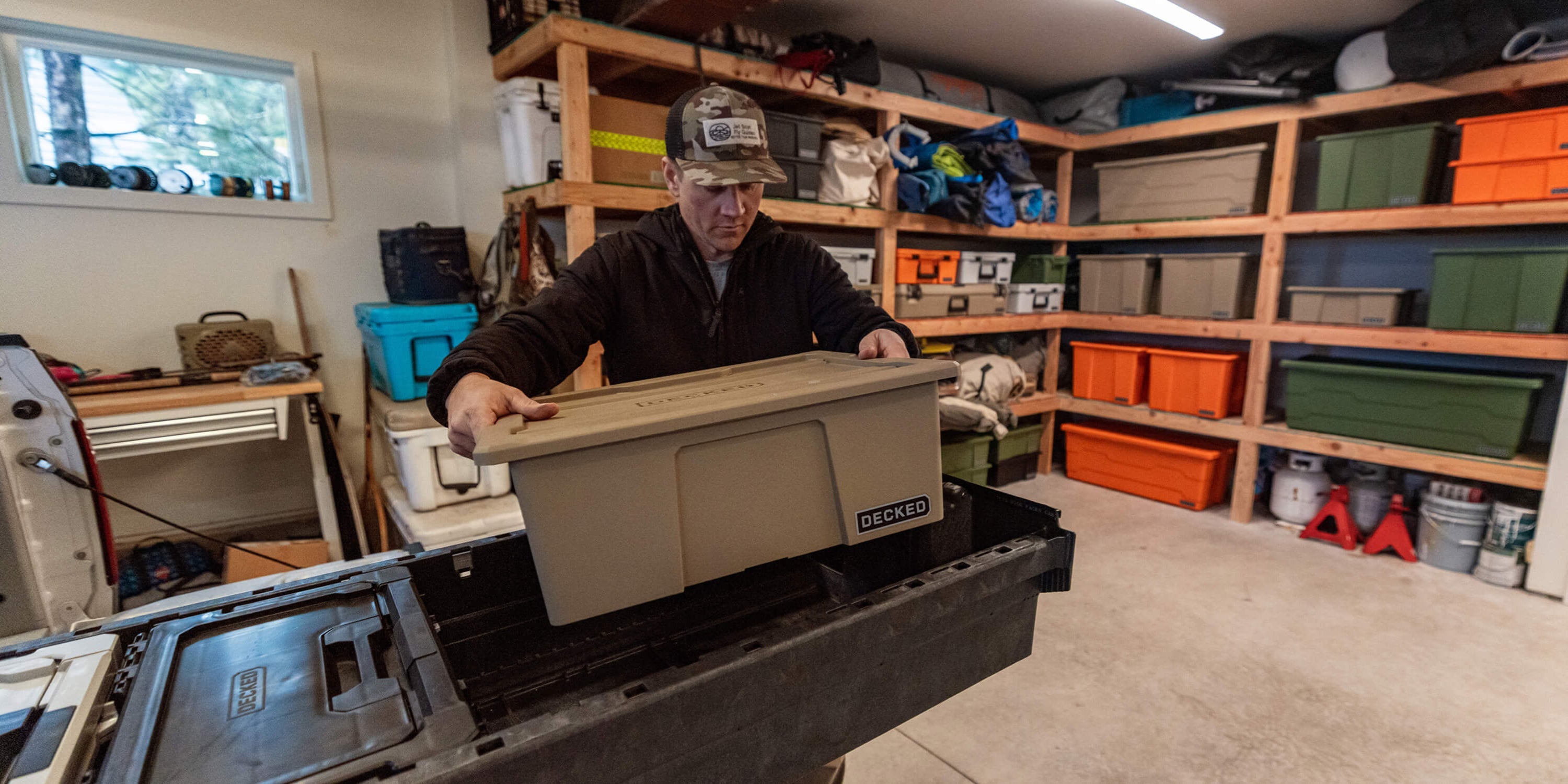 [A0041-DBIN-TAN, A0040-DBIN-XXX] @expanded A man loading a single desert tan Payloader Bin into a DECKED Drawer System in his garage.
