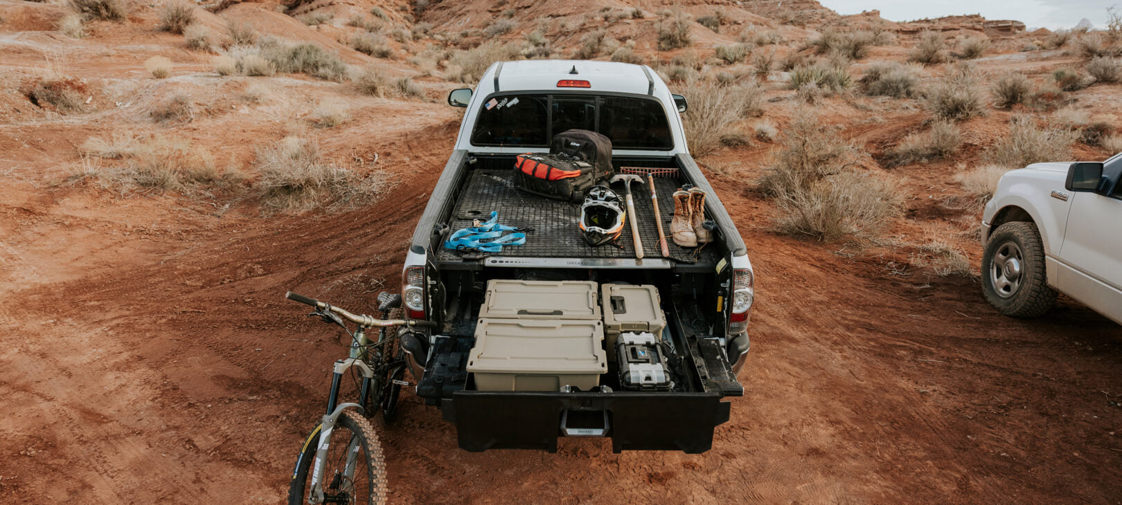 @expanded [A0077-BMYL-BLK, A0078-BMYS-BLK] A battle mat on a Drawer System out in the desert, piled high with biking gear.