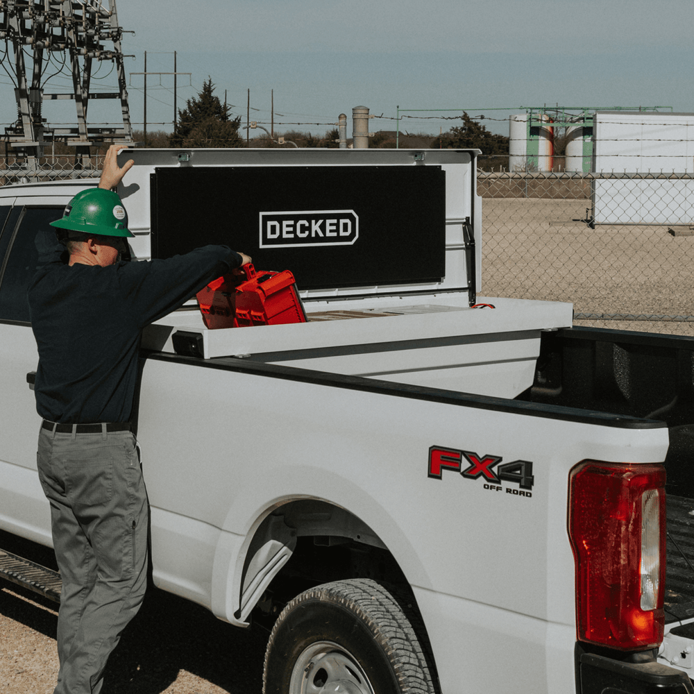 [DTB2-WHT, DTB2T22-WHT] Person loading a truck with a 'DECKED' Tool Box in an industrial setting
