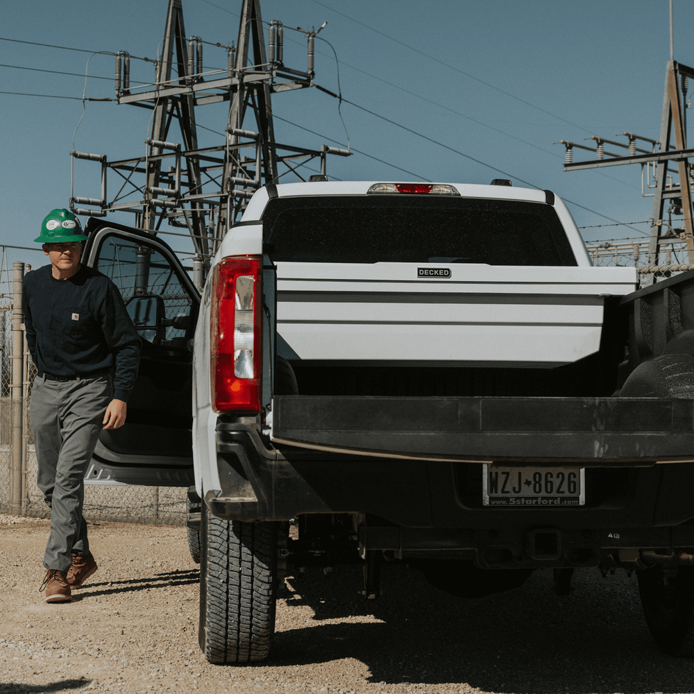 [DTB2-WHT, DTB2T22-WHT] Person standing next to a white truck with a white DECKED Tool Box with a clear sky background