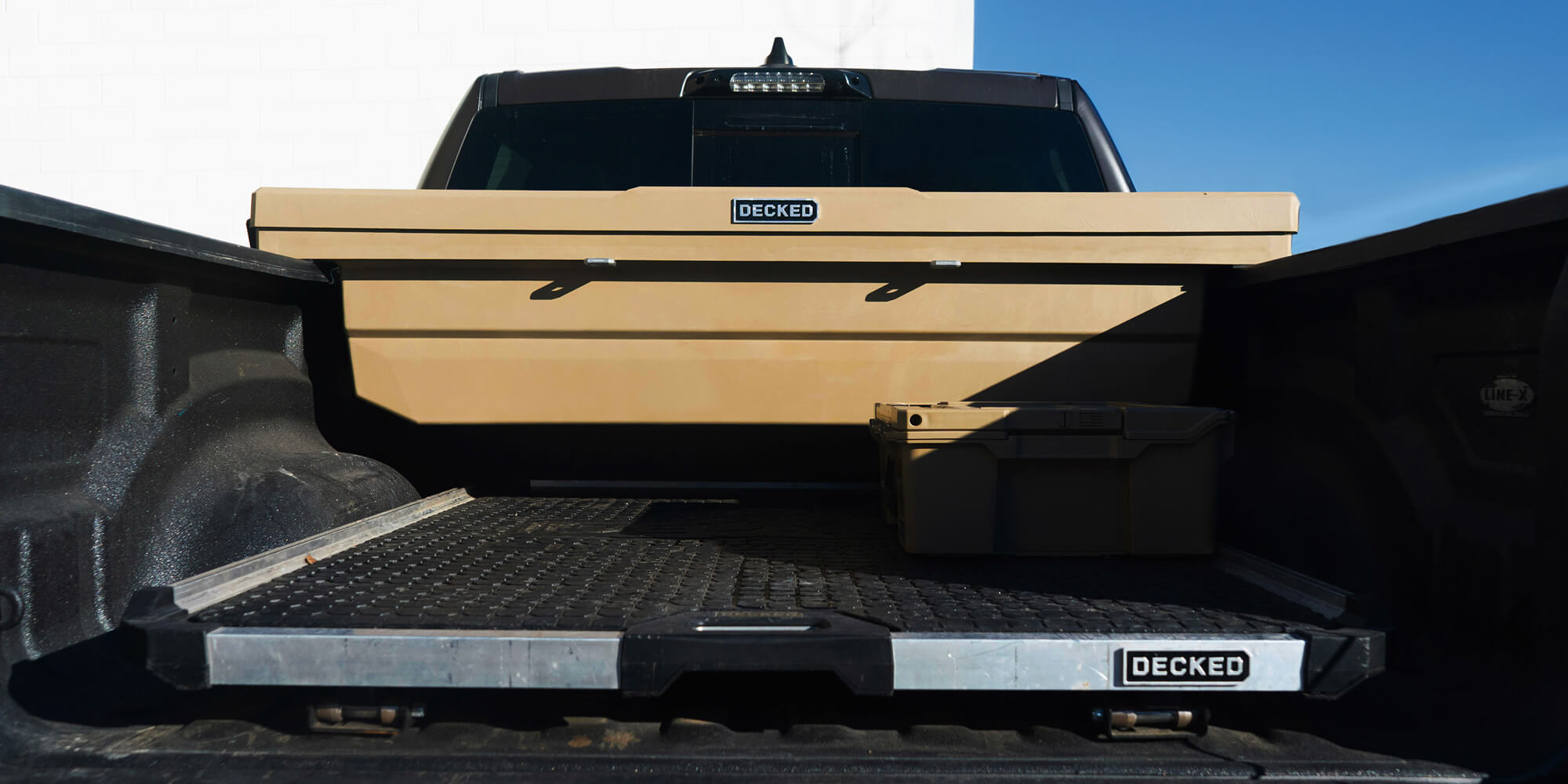 @expanded [DTB2-BLK, DTB2-WHT, DTB2-TAN, DTB2T22-BLK, DTB2T22-WHT, DTB2T22-TAN] Truck bed with a DECKED Tool Box and CargoGlide storage system against a blue sky.